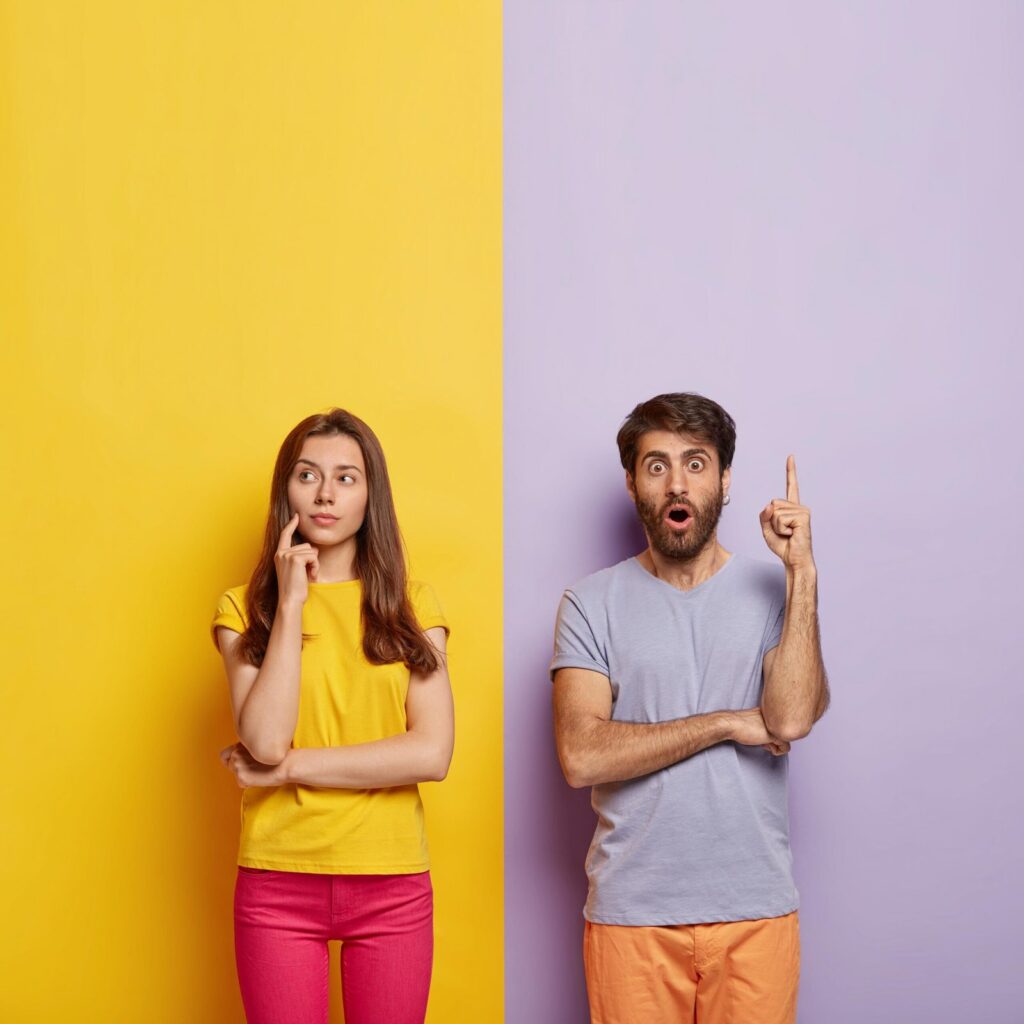 shocked millennial couple posing against dual colored wall scaled 1